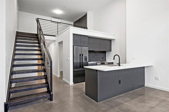 kitchen with kitchen peninsula, sink, appliances with stainless steel finishes, and concrete flooring