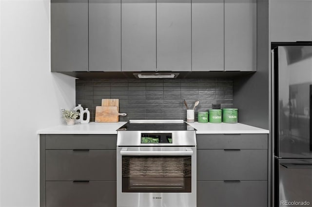 kitchen featuring stainless steel appliances, gray cabinets, and tasteful backsplash