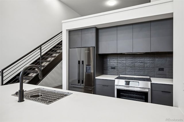 kitchen with tasteful backsplash, light countertops, gray cabinets, stainless steel appliances, and modern cabinets