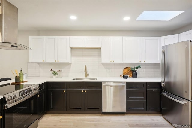 2121 W 33rd Ave, Denver, CO 80211 - kitchen with appliances with stainless steel finishes, wall chimney exhaust hood, a skylight, white cabinetry, and light countertops