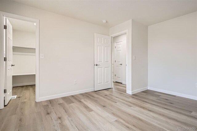 unfurnished bedroom featuring a closet, a spacious closet, and light hardwood / wood-style flooring