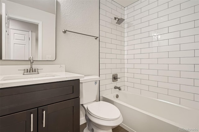 full bathroom featuring tiled shower / bath, vanity, and toilet