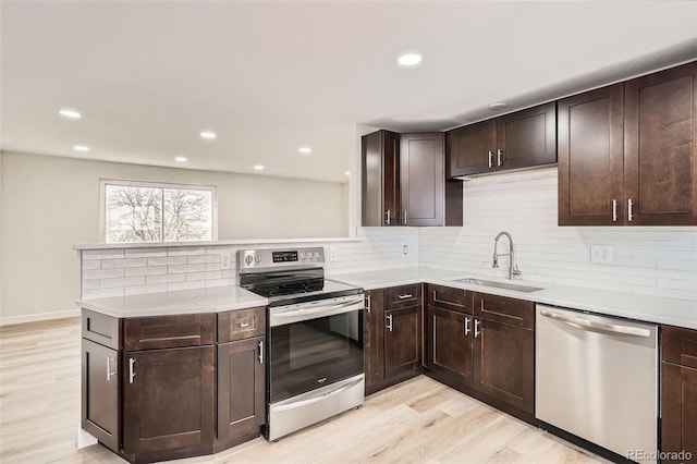 kitchen with tasteful backsplash, sink, dark brown cabinetry, stainless steel appliances, and light wood-type flooring