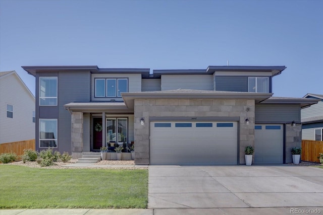 prairie-style home with driveway, a garage, stone siding, fence, and a front yard