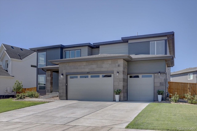 view of front of house featuring stone siding, concrete driveway, fence, and an attached garage