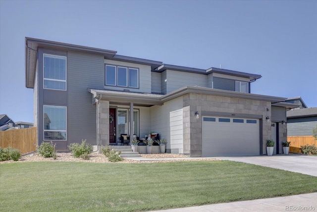 prairie-style home with a garage, driveway, fence, and a front yard