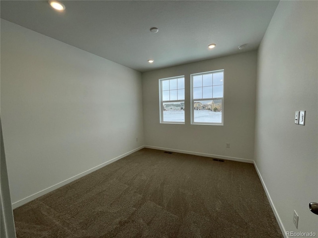 empty room featuring dark colored carpet, baseboards, and recessed lighting