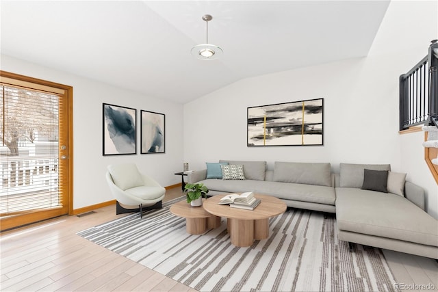 living area featuring light wood finished floors, baseboards, visible vents, and vaulted ceiling