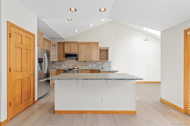 kitchen featuring glass insert cabinets, a sink, light wood-style floors, and appliances with stainless steel finishes