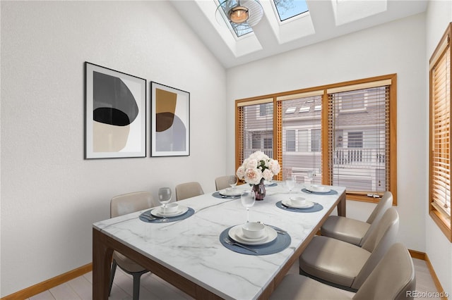 dining room featuring baseboards and lofted ceiling with skylight