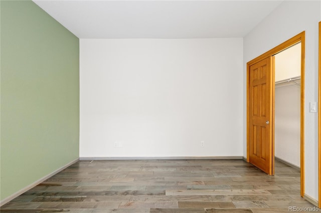 unfurnished bedroom featuring a closet, baseboards, and wood finished floors