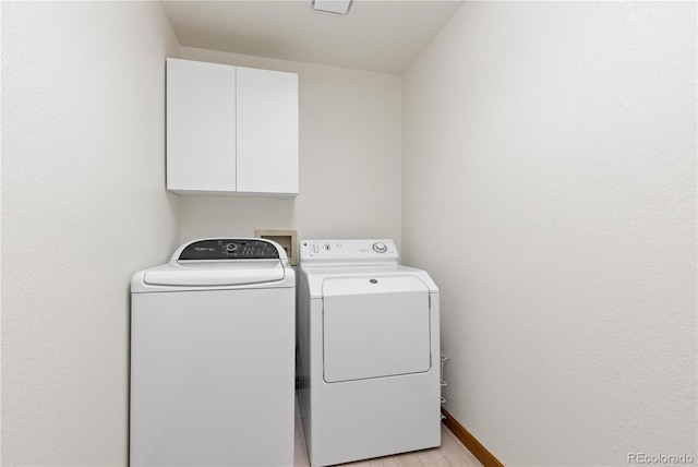 washroom with independent washer and dryer, light wood-type flooring, cabinet space, and baseboards