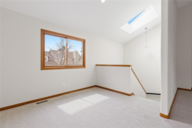 spare room featuring baseboards, carpet flooring, visible vents, and lofted ceiling with skylight