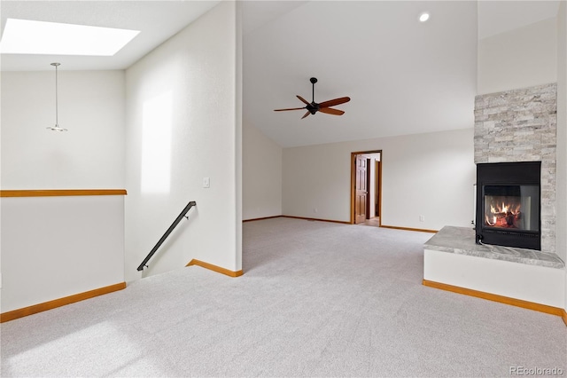 unfurnished living room with baseboards, a fireplace, lofted ceiling with skylight, and carpet