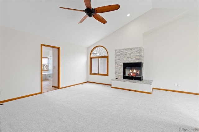 unfurnished living room featuring a stone fireplace, a ceiling fan, light carpet, and a healthy amount of sunlight