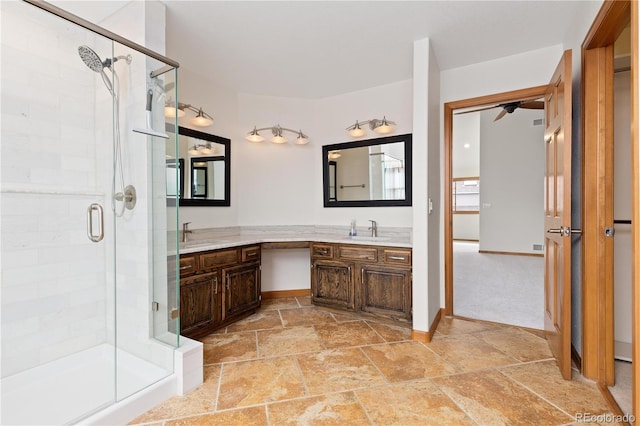 full bathroom featuring vanity, baseboards, a shower stall, and stone finish flooring