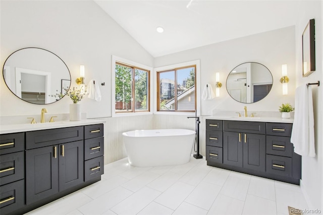9810 Venneford Ranch Rd, Highlands Ranch, CO 80126 - bathroom featuring lofted ceiling, two vanities, a soaking tub, tile patterned flooring, and wainscoting