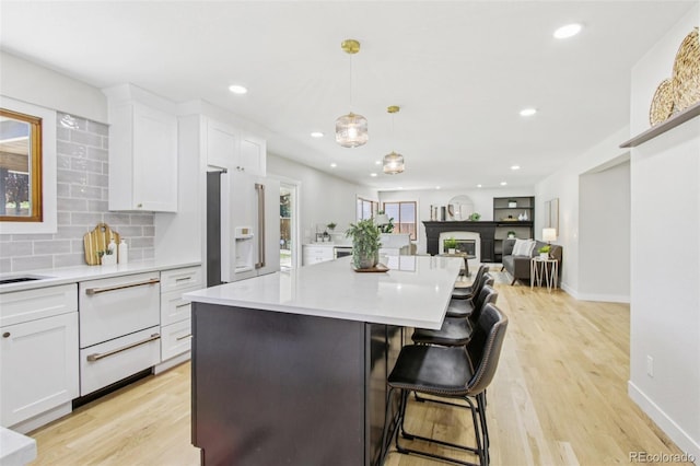 9810 Venneford Ranch Rd, Highlands Ranch, CO 80126 - kitchen featuring white refrigerator with ice dispenser, white cabinetry, light countertops, light wood-style floors, and recessed lighting