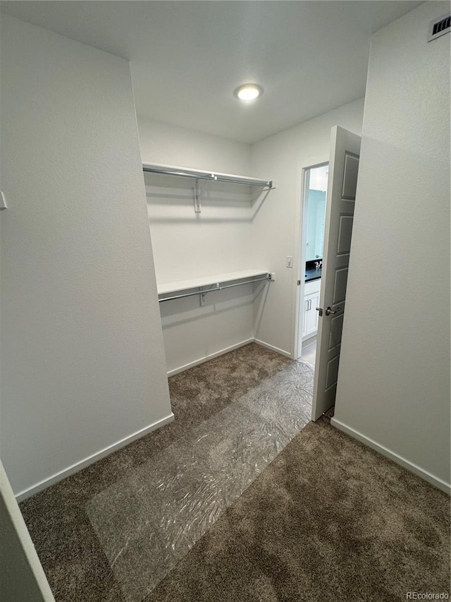 walk in closet featuring dark colored carpet