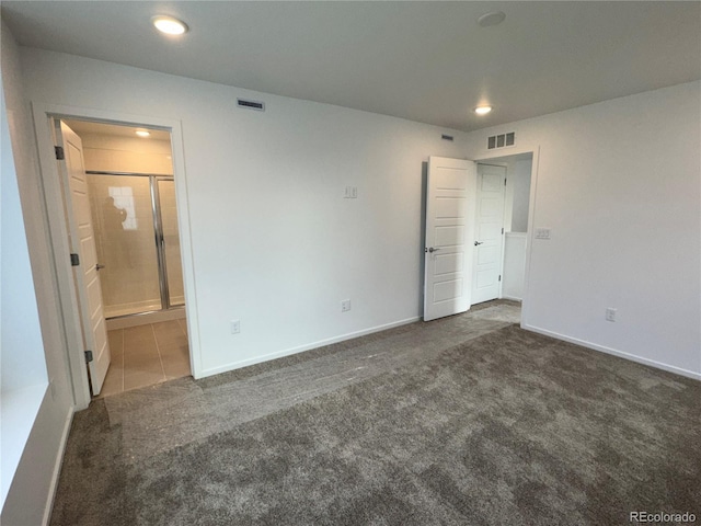 unfurnished bedroom featuring connected bathroom and dark carpet