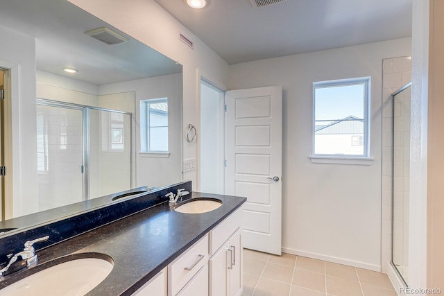 bathroom with a healthy amount of sunlight, tile patterned flooring, a shower with door, and vanity