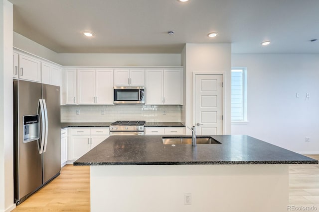 kitchen with white cabinetry, stainless steel appliances, and a center island with sink