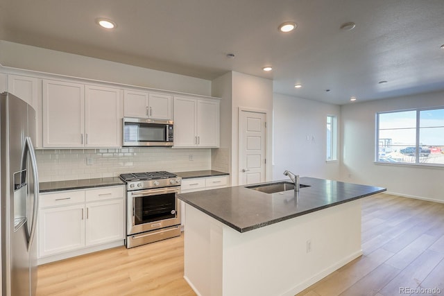 kitchen with sink, a center island with sink, light wood-type flooring, appliances with stainless steel finishes, and white cabinets