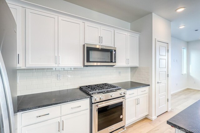 kitchen featuring white cabinetry, decorative backsplash, stainless steel appliances, and light hardwood / wood-style floors