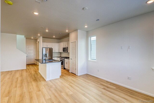 kitchen with sink, a center island with sink, appliances with stainless steel finishes, light hardwood / wood-style floors, and white cabinets