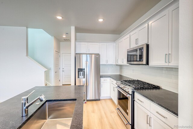 21242 E 63rd Dr, Aurora, CO 80019 - kitchen with appliances with stainless steel finishes, a sink, white cabinets, light wood-style flooring, and recessed lighting
