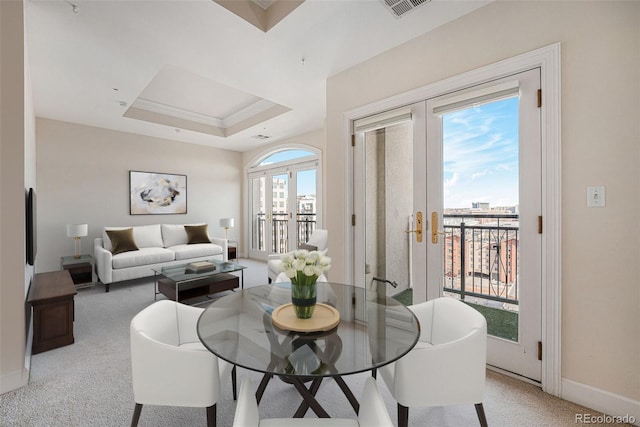 dining area with light colored carpet, french doors, and a tray ceiling