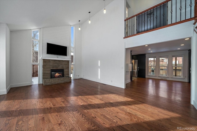 unfurnished living room featuring a brick fireplace, high vaulted ceiling, and dark hardwood / wood-style flooring