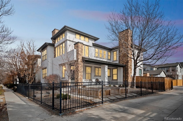 view of front of property with stone siding, a fenced front yard, a chimney, and stucco siding