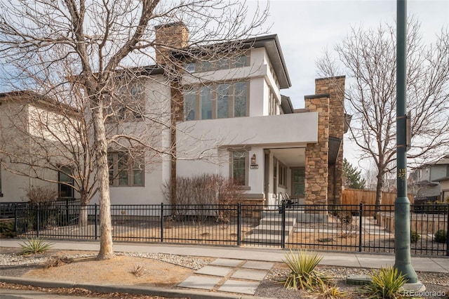 view of front of property with a fenced front yard, a chimney, and stucco siding