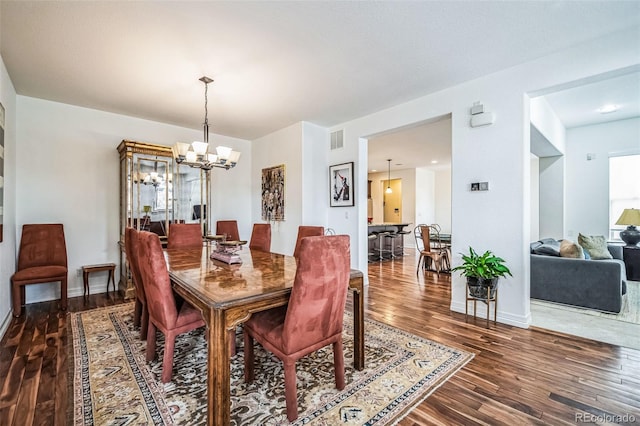 dining space featuring a chandelier, visible vents, baseboards, and wood finished floors