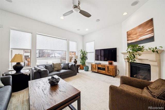 living area with recessed lighting, a glass covered fireplace, a ceiling fan, and light colored carpet