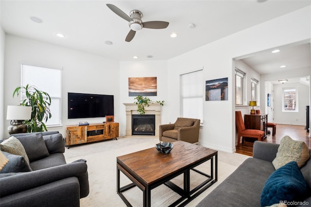 living area with baseboards, a glass covered fireplace, and recessed lighting