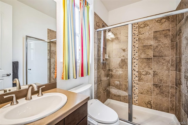 bathroom with vanity, a shower stall, and toilet