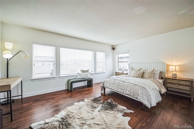 bedroom featuring dark wood finished floors, a textured ceiling, and baseboards