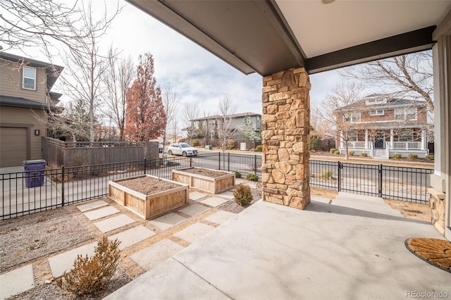 view of patio featuring a residential view, a garden, and fence