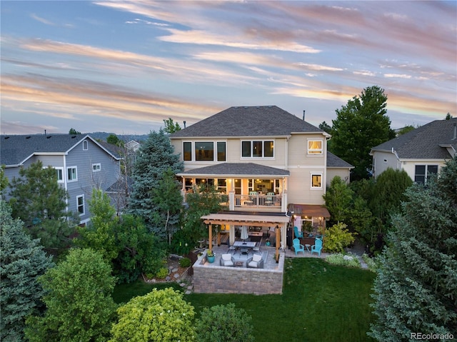 back house at dusk with a yard, a balcony, and a patio