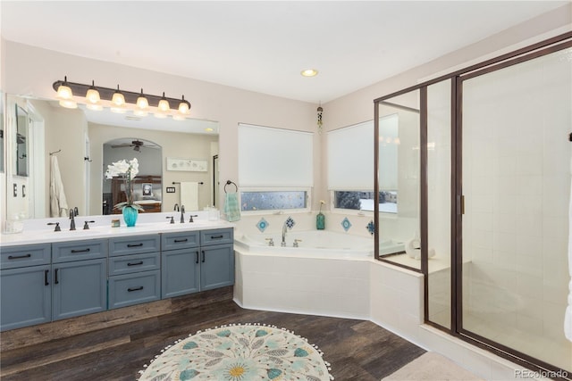 bathroom featuring vanity, ceiling fan, plus walk in shower, and hardwood / wood-style flooring