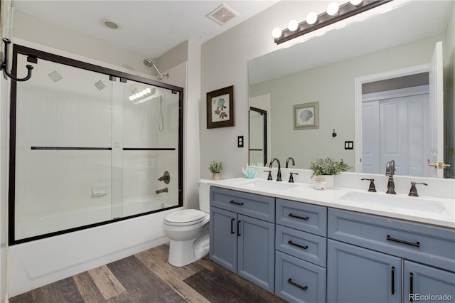 full bathroom featuring enclosed tub / shower combo, toilet, wood-type flooring, and vanity