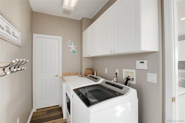 laundry area featuring washing machine and dryer, dark wood-type flooring, cabinets, and sink