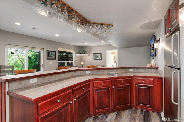 kitchen with stainless steel fridge, dark hardwood / wood-style flooring, tile counters, and sink