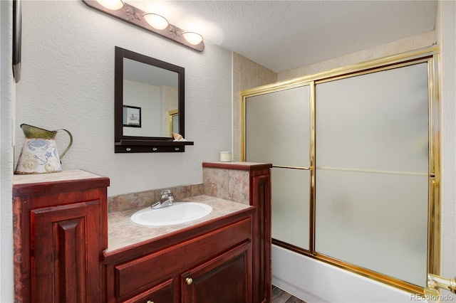 bathroom with shower / bath combination with glass door, hardwood / wood-style floors, vanity, and a textured ceiling