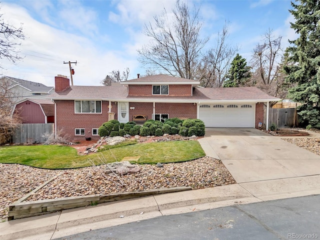 split level home featuring an attached garage, a front yard, fence, and brick siding
