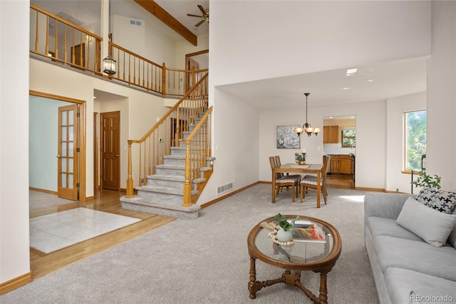 6506 S Robb Way, Littleton, CO 80127 - living room with a towering ceiling, carpet flooring, a chandelier, stairs, and wood finished floors