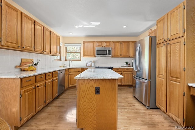 6506 S Robb Way, Littleton, CO 80127 - kitchen featuring appliances with stainless steel finishes, a center island, light wood finished floors, tasteful backsplash, and light stone counters
