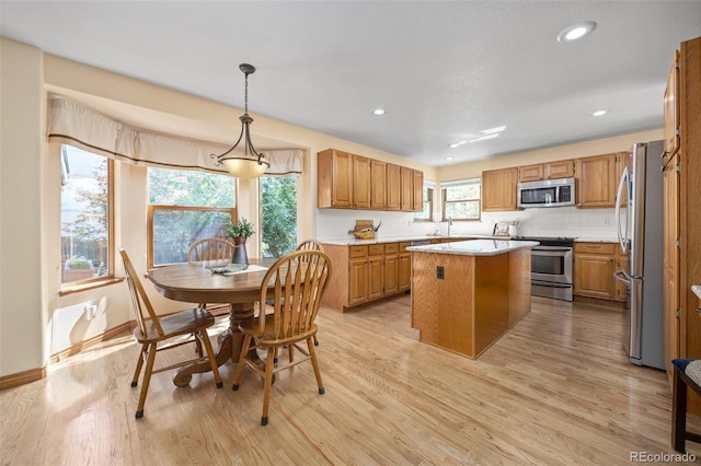 6506 S Robb Way, Littleton, CO 80127 - kitchen featuring stainless steel appliances, light countertops, light wood finished floors, a center island, and backsplash